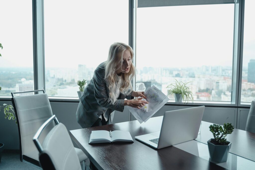 Professional businesswoman in modern office conducting virtual meeting with documents and laptop.
